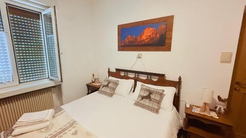 a bedroom with a bed with white sheets and pillows at Dimora Il Feudo - Predazzo in Predazzo