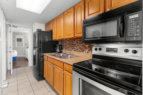 a kitchen with a stove and a microwave and a sink at Monterey Bay Suites in Myrtle Beach
