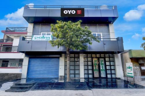 a building with a tree in front of it at Hotel O Palm Inn Durgapura Railway Station in Jaipur