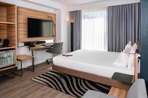 a hotel room with a bed and a desk and a tv at Novotel London Canary Wharf in London