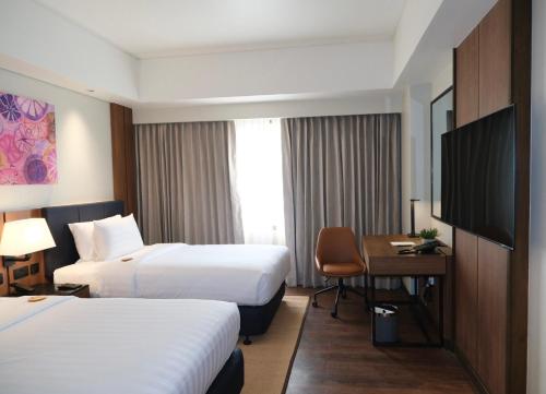a hotel room with two beds and a desk and a television at Seda Abreeza - Newly Renovated in Davao City