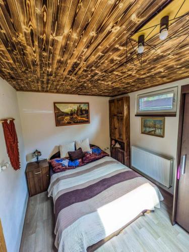 a bedroom with a bed and a wooden ceiling at Chata u Rybníka in Žďár nad Sázavou