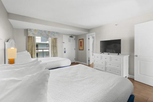 a white bedroom with two beds and a flat screen tv at Monterey Bay Suites in Myrtle Beach