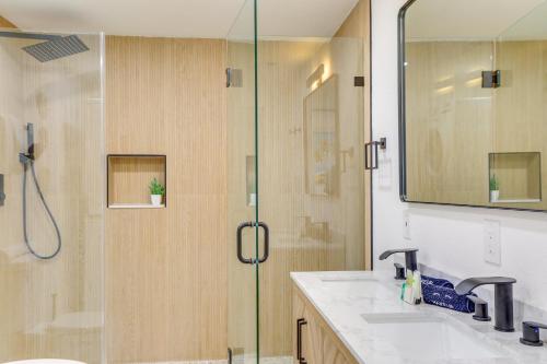 a bathroom with a shower with two sinks and a glass door at Private Hot Tub and Fenced Yard Sleek Gulfport Home in St Petersburg