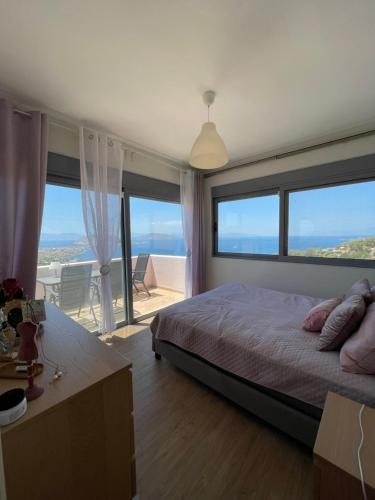 a bedroom with a large bed and large windows at Casa MareLuna in Egina