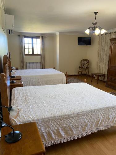 a bedroom with two beds and a tv on the wall at Quinta do Azibo in Podence