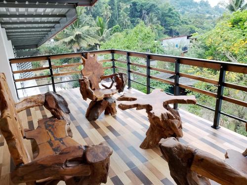 a balcony with wooden chairs and a view of the forest at kites mountain in Badulla