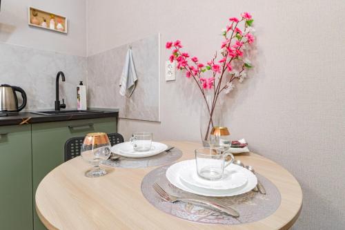 a table with two plates and a vase with flowers on it at Цветущий сад in Astana