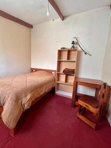 a bedroom with a bed and a table and a shelf at Casa de Liz in Sucre