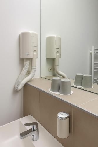 a bathroom with a sink and two mirrors at Hôtel de la Poste Martigny - City Center in Martigny-Ville