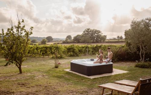 a man and woman sitting in a hot tub in a field at Agriturismo La Vecchia Quercia in Montemerano