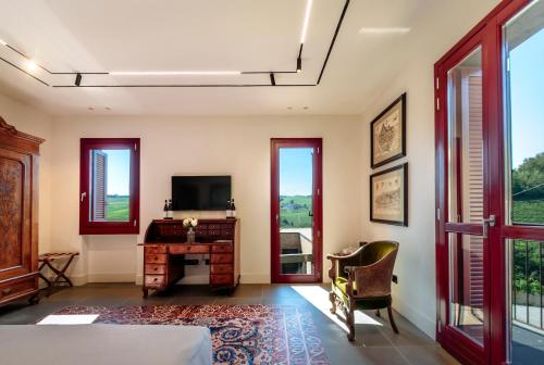 a bedroom with a desk and a television and windows at Foresteria, Winery & Events Destination in Monforte dʼAlba