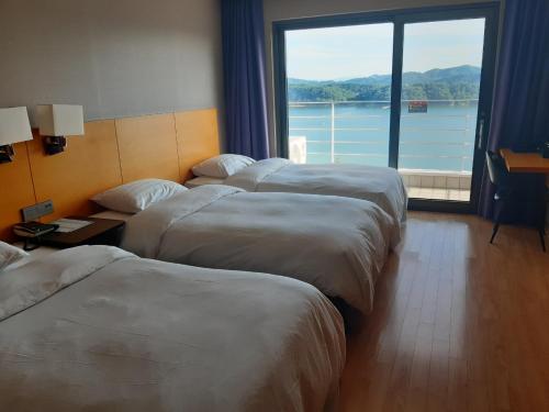 a row of beds in a hotel room with a large window at Asia Lakeside Hotel in Jinju