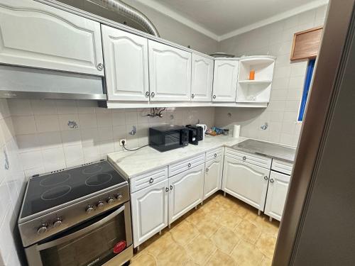 a kitchen with white cabinets and a stove top oven at Milennium Holiday Apartment in Quarteira