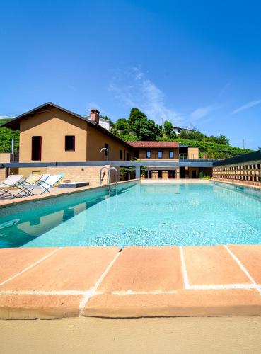 a large swimming pool with chairs and a building at Foresteria, Winery & Events Destination in Monforte dʼAlba