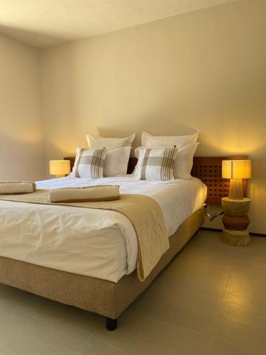 une chambre avec un grand lit avec des draps et des oreillers blancs dans l'établissement Les bois de Capra Scorsa, à Belgodère