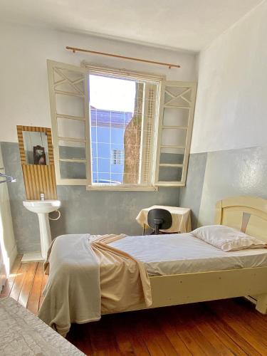 a bedroom with a bed and a sink and a window at Hotel Avenida Bauru in Bauru