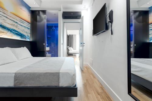 a bedroom with a bed and a flat screen tv at Hibrido Boutique Hotel & Spa in Sciacca
