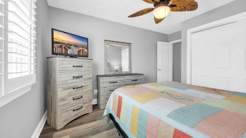 a bedroom with a bed and a dresser and a television at Relaxing Cherry Grove Beach House with Balcony Family Fun in Myrtle Beach