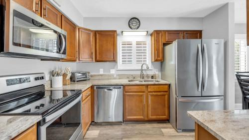 a kitchen with wooden cabinets and stainless steel appliances at Relaxing Cherry Grove Beach House with Balcony Family Fun in Myrtle Beach