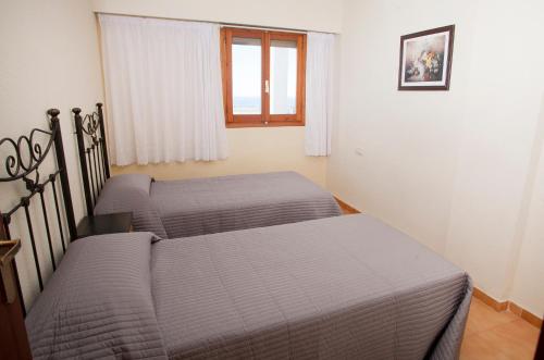 two twin beds in a room with a window at Complejo Bellavista Residencial in Pego
