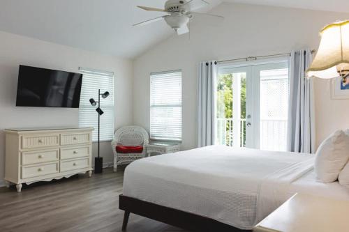 a bedroom with a bed and a dresser with a tv at New Casa Caribe by Brightwild- Two-Story Condo Rooftop Pool in Key West