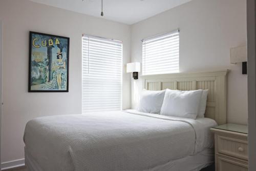 a white bedroom with a bed and a window at New Casa Caribe by Brightwild- Two-Story Condo Rooftop Pool in Key West