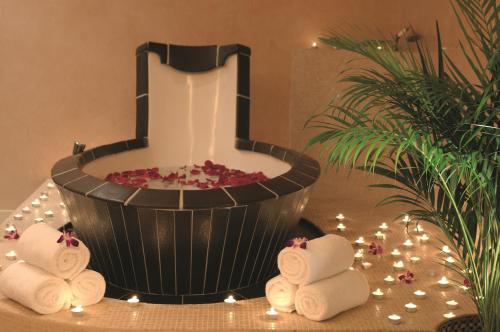 a spa room with a wellness tub and towels at Mövenpick Hotel & Resort Al Bida'a in Kuwait