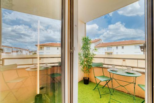 un balcon avec une table, des chaises et une fenêtre dans l'établissement Le Verde - Ravissant appartement cosy, à Saint-Genis-Laval