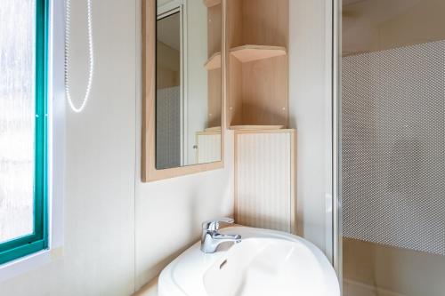 une salle de bain blanche avec un lavabo et un miroir dans l'établissement Camping Au Bois Dormant, à Chauffour-sur-Vell