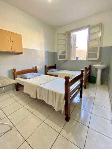 a bedroom with two beds and a sink in it at Hotel Avenida Bauru in Bauru