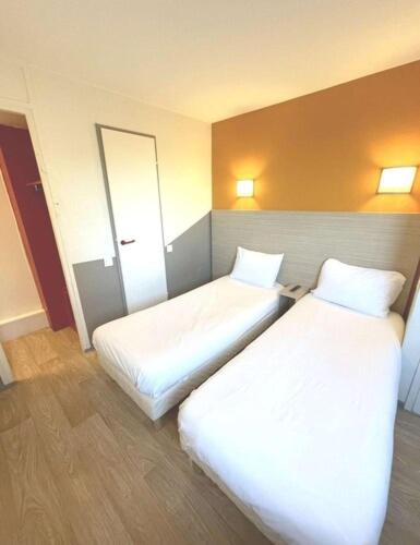 two beds in a hotel room with white sheets at Première Classe Toulouse Nord - L'Union in LʼUnion
