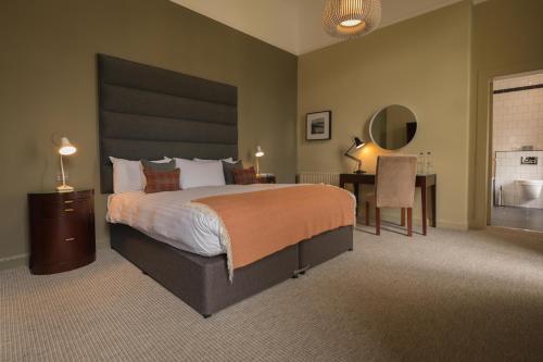 a large bedroom with a large bed and a desk at Peebles Hydro in Peebles