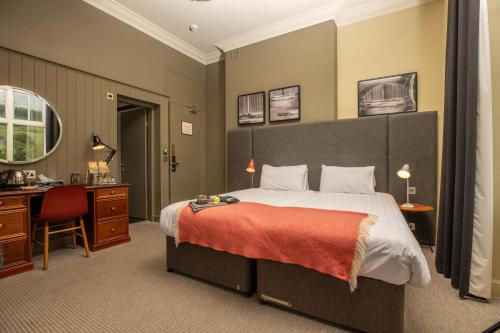 a bedroom with a large bed and a desk and a desk at Peebles Hydro in Peebles