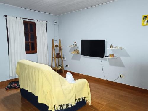 sala de estar con sofá amarillo y TV en AlojamientolaFamilia, en Puerto Iguazú