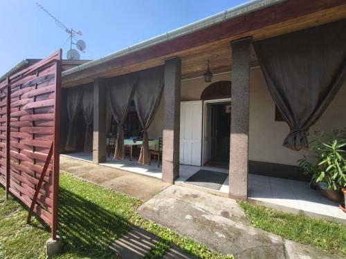 a house with a porch with curtains on it at Anna Vendégház in Kápolnásnyék