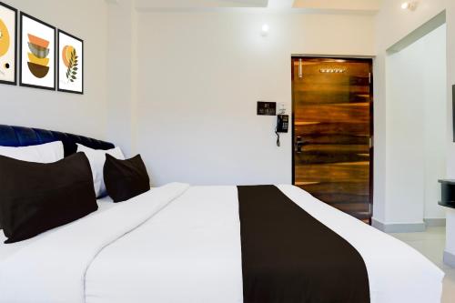 a bedroom with a white bed and a wooden door at Hotel O AAGAMAN HOTEL & RESTAURANT in Begusarai