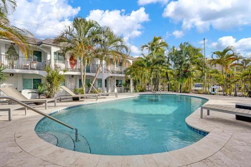 a swimming pool in a courtyard with palm trees at Bright Beachside Getaway in Pompano Beach