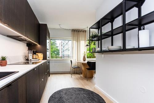 a kitchen with wooden cabinets and a large window at UPEA keskustan kaksio in Kuopio