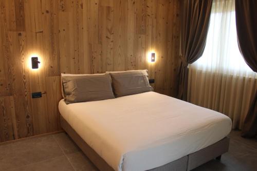 a bed with white sheets and pillows in a bedroom at Oltre Alpine Hotel in Bormio