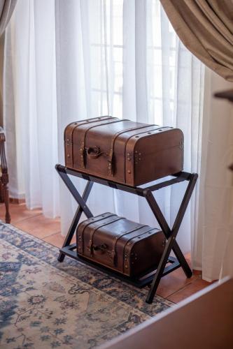 two suitcases on a stand next to a window at Hotel Palacio de Hemingway in Ronda