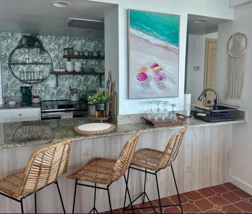 a kitchen with a bar with chairs and a painting at Daytona oceanfront two-bedroom suite in Daytona Beach