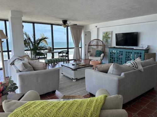 a living room with couches and a television and the ocean at Daytona oceanfront two-bedroom suite in Daytona Beach
