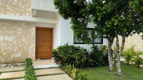 a house with a wooden door and some plants at Ecos del Mar - Villa tranquila y privada a 15 mins de la playa - Punta Cana in Punta Cana
