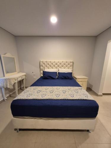 a bedroom with a bed with a blue comforter at Tu casa moderna con Quincho in Asuncion