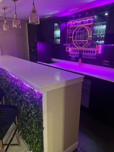 a bar with purple lighting in a nightclub at Golden Crown exclusive use spa venue in Tarbolton