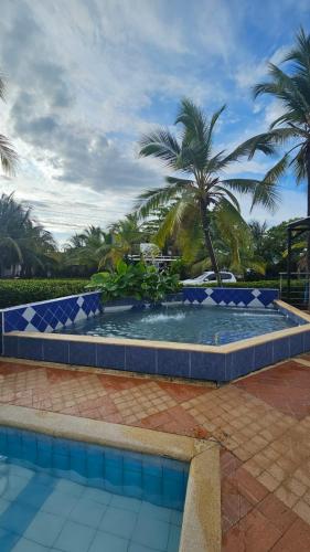a large pool with blue tiles on it with palm trees at Cabañas Ana Sofía in San Antero