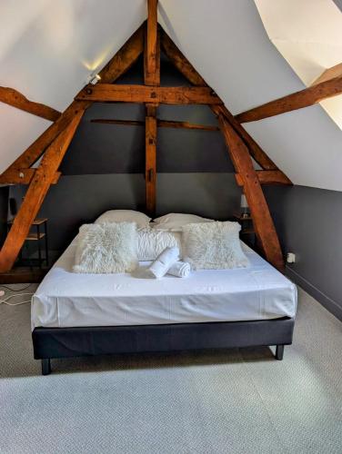 - une chambre avec un lit blanc et des poutres en bois dans l'établissement La maison au bord de la riviére, à Loches