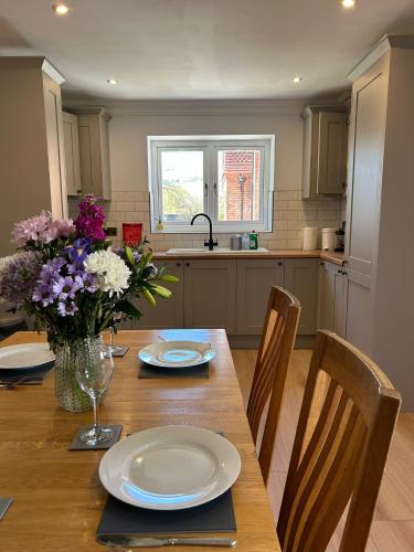 a kitchen with a wooden table with a vase of flowers at Goring River Retreat with Gym and Wellness Area in Goring