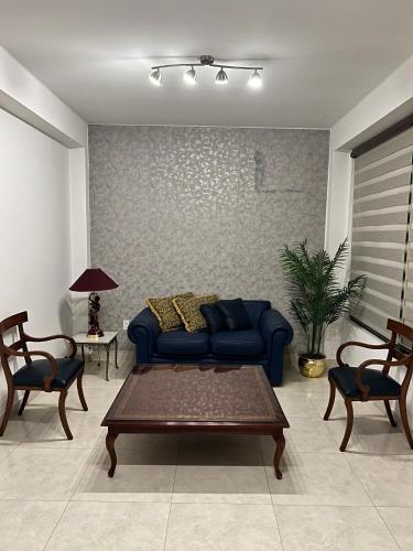 a living room with a blue couch and a table at Apartamento de 2 habitaciones en el centro de Tarija! in Tarija